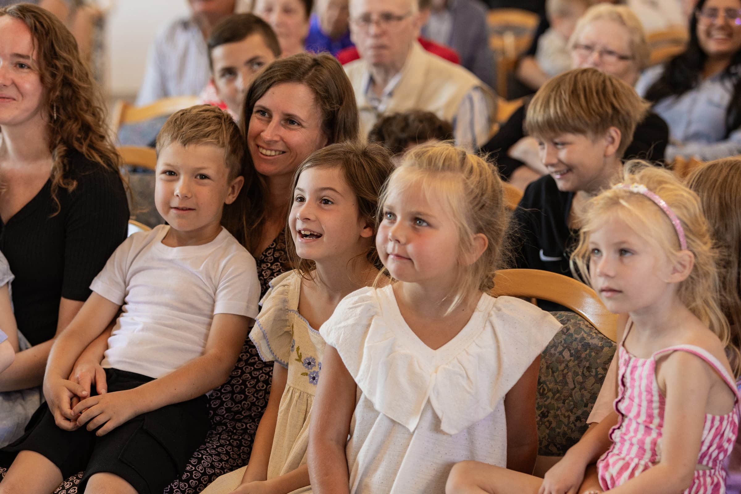 Kinder sitzen mit ihren Familien in der ersten Reihe und hören zu